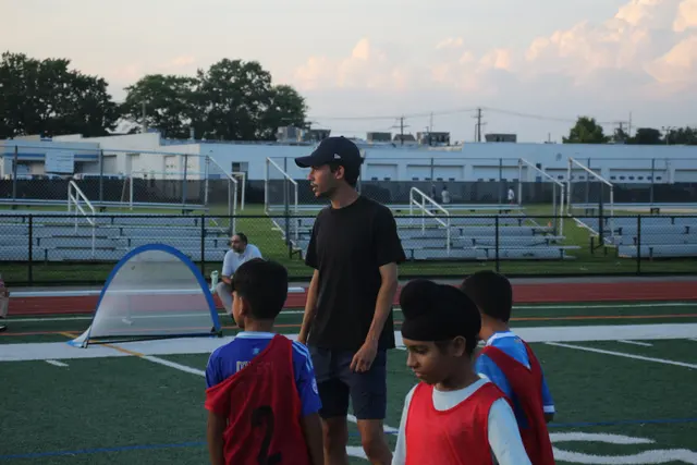 Players in red bibs listening to a coach during a session
