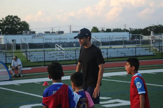 Coach Josh giving instructions to players gathered around him on the field